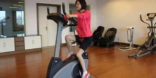 微笑的女人在健身房里做动感单车运动