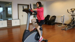 微笑的女人在健身房里做动感单车运动视频素材模板下载