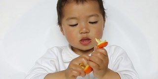 亚洲小孩认真地撕着橘子瓤，嘴唇抽动着