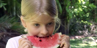 微笑的小女孩吃红色的西瓜水果在户外