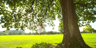 高清慢镜头:小女孩在绿树下荡秋千