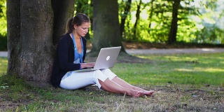 年轻女子在公园用笔记本电脑