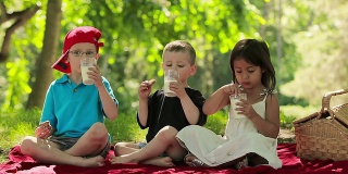三个孩子吃饼干和牛奶的乐趣。