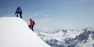 攀登者互相帮助到达白雪覆盖的山峰