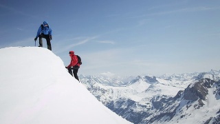 攀登者互相帮助到达白雪覆盖的山峰视频素材模板下载