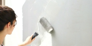 年轻女子正在用油漆滚筒刷墙
