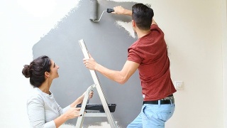 年轻夫妇用油漆滚筒刷墙视频素材模板下载