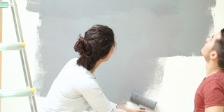 年轻夫妇用油漆滚筒刷墙