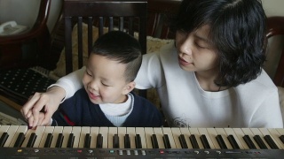 一位中国母亲教她的儿子弹钢琴视频素材模板下载