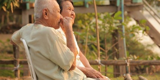 Senior couple sitting near river during sunset