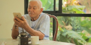 快乐的亚洲老人在家里用手机