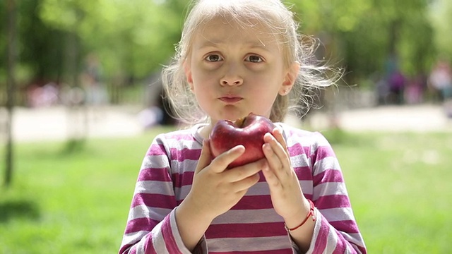 小女孩在操场上吃苹果