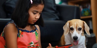 一个非洲小女孩在用她的平板电脑，她的小猎犬在看平板电脑