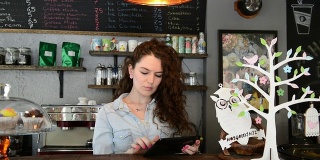 年轻女咖啡师在用平板电脑