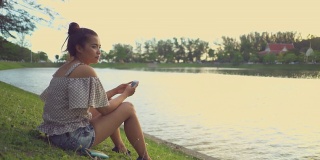 亚洲女性在河边使用智能手机的慢镜头