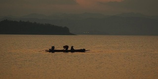 画面:黄昏时分，渔民在大坝上的长船上捕鱼