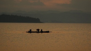 画面:黄昏时分，渔民在大坝上的长船上捕鱼视频素材模板下载