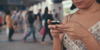 慢镜头:一名亚洲女子在城市场景中看智能手机上的信息