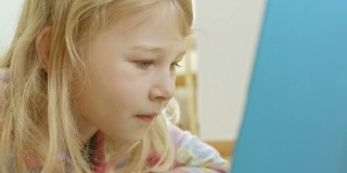 小女孩在笔记本电脑上看书