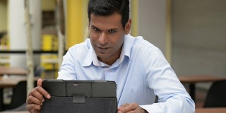 兴高采烈的印度商人在户外咖啡馆使用数字平板电脑