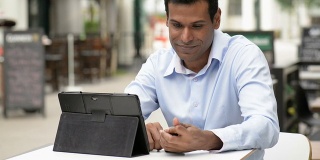 印度商人在户外咖啡馆使用数字平板电脑
