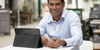 兴高采烈的印度商人在户外咖啡馆使用数字平板电脑