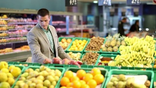 超市水果柜台旁推着手推车的人视频素材模板下载