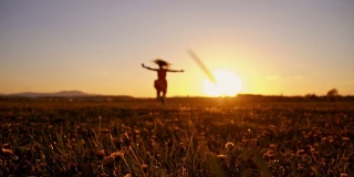 SLO MO快乐的女孩在日落的草地上旋转