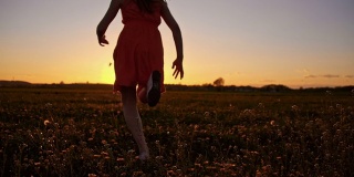 日落时分，快乐的女孩在草地上奔跑