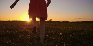 SLO MO女孩跑和跳在草地在日落