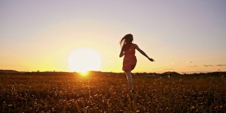 日落时分，快乐的女孩在草地上奔跑