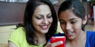 亚洲印度母亲和女儿使用手机阅读短信