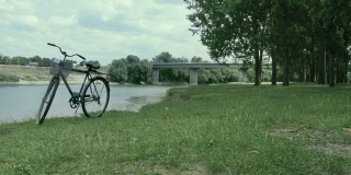 自行车站在离桥不远的河岸上