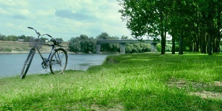自行车站在离桥不远的河岸上