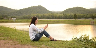 年轻女子在大自然中触摸智能手机