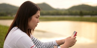 年轻女子在大自然中触摸智能手机