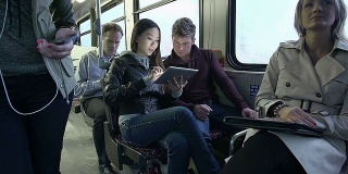 在公交车上玩平板电脑的通勤者
