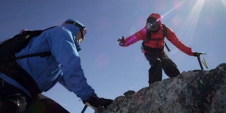 登山者在山上互相帮助翻越岩石