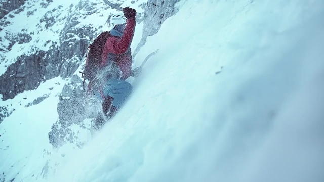 冬季登山者挥舞着他的斧头爬上积雪的斜坡