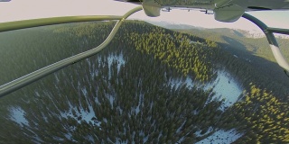 在阳光明媚的冬日里，POV直升机飞过森林
