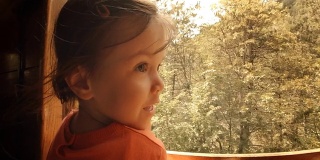 火车上的孩子——一个小女孩享受她的第一次火车旅行。山景窗外。