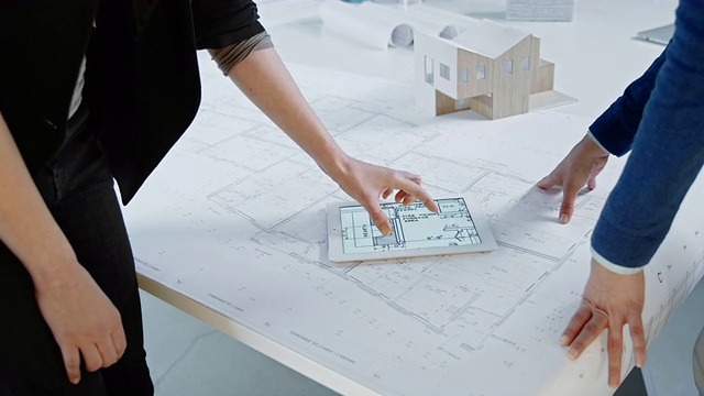 女性建筑师使用平板电脑，讨论平面图，握手