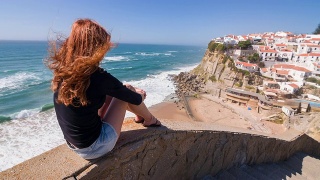 女游客俯瞰海边悬崖上的村庄视频素材模板下载