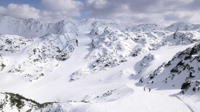在阳光明媚的日子里，空中滑雪者沿着滑雪坡滑行
