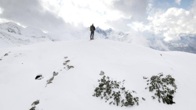 空中滑雪旅行者得意洋洋地在山顶举起双手