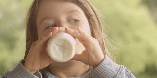 3岁的孩子在一个美丽的夏天早晨在门廊享受牛奶
