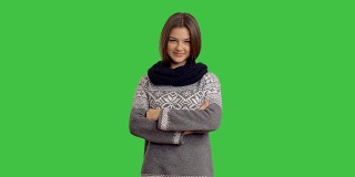 绿色背景下穿着冬季毛衣的年轻漂亮的女人
