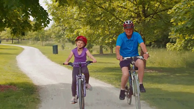 孙女和爷爷骑着自行车穿过公园