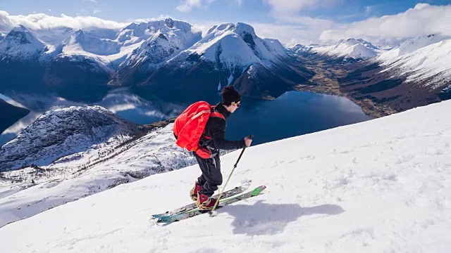 滑雪者爬上山，背景是挪威峡湾
