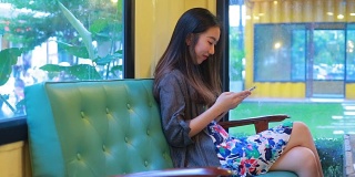 美丽的亚洲女孩打字手机在咖啡店